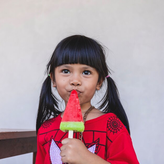 Une petite fille asiatique mange joyeusement de la glace.