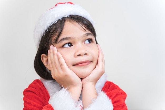 Une petite fille asiatique mignonne dans une robe rouge de père Noël décorant l'arbre de Noël la veille de Noël