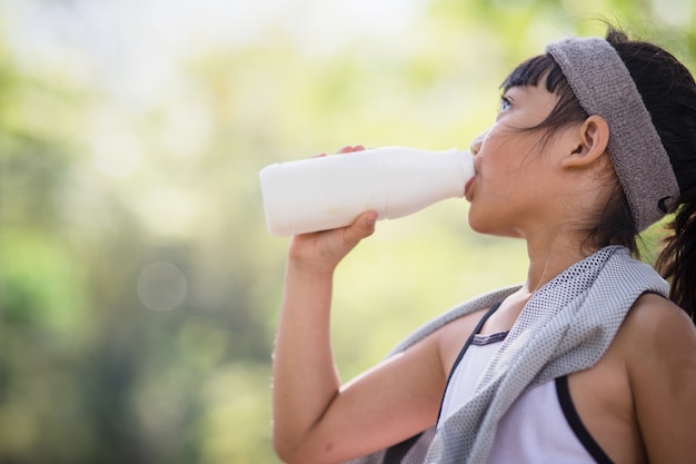 La petite fille asiatique mignonne d'enfant boit un lait, foyer mou