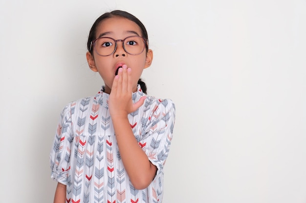 Petite fille asiatique montrant une expression choquée avec une main couvrant sa bouche