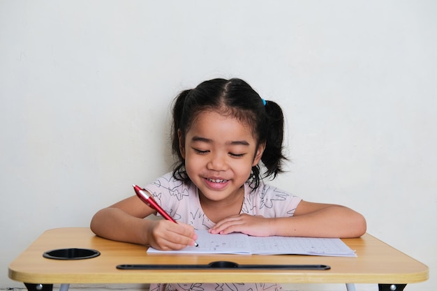 Petite fille asiatique montrant l'expression du visage heureux pendant l'étude