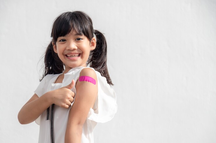Photo petite fille asiatique montrant son bras après s'être fait vacciner ou vacciner l'enfant vacciné