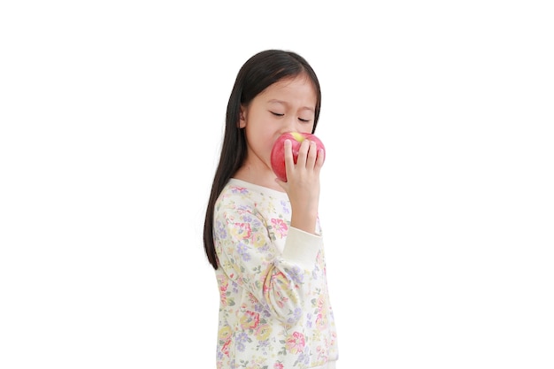 Petite fille asiatique mordre pomme rouge isolé sur fond blanc