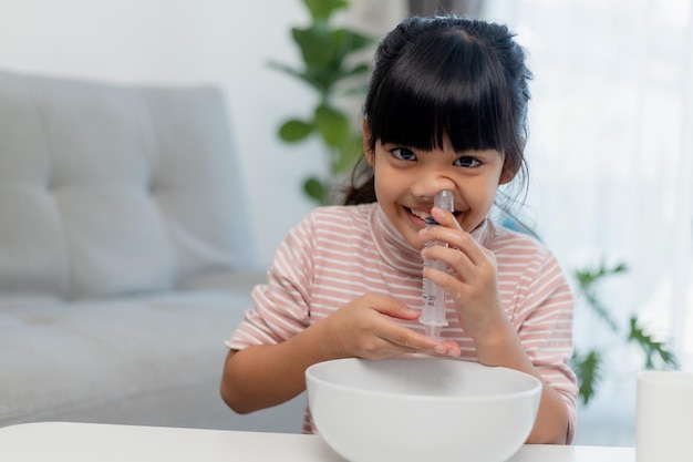 Petite fille asiatique nez de lavage nasal salin à la maison