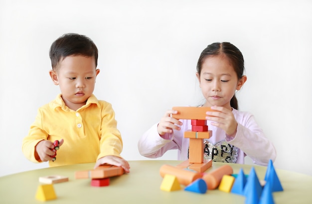 Petite fille asiatique et petit garçon jouant avec des jouets en bois