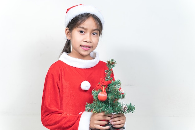 Petite fille asiatique portant un costume de père Noël rouge pour célébrer les vacances de Noël à la maison