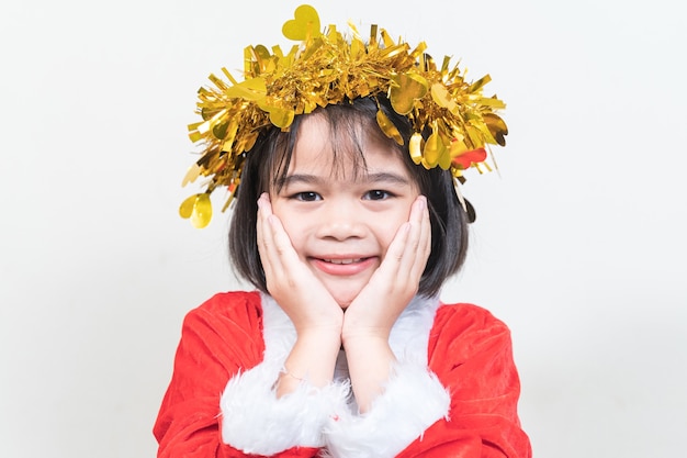 Petite fille asiatique portant un costume de père Noël rouge pour célébrer les vacances de Noël à la maison