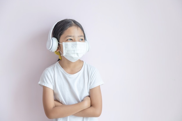 Photo une petite fille asiatique portant un masque de protection médical et des écouteurs