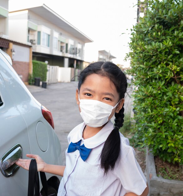 Une petite fille asiatique porte un uniforme et un masque de protection