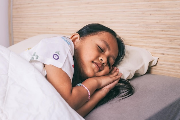 Une petite fille asiatique en pyjama qui dort dans une chambre.