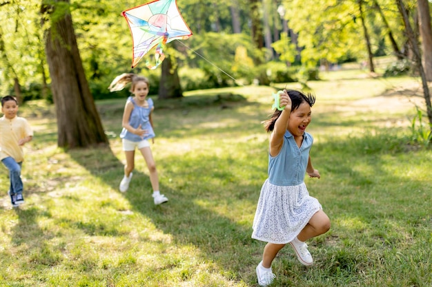 Petite fille asiatique qui court joyeusement avec un cerf-volant dans le parc