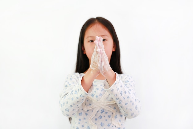 Petite fille asiatique se lavant les mains avec de l'eau et du savon sur fond blanc. Concentrez-vous à portée de main