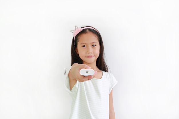 Petite fille asiatique tenant une télécommande isolée sur fond blanc.