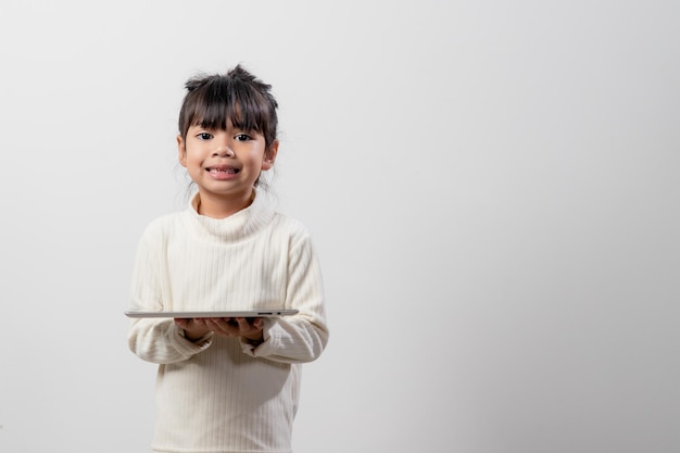 Petite fille asiatique tenant et utilisant la tablette numérique sur fond de studio blanc espace de copie gratuit