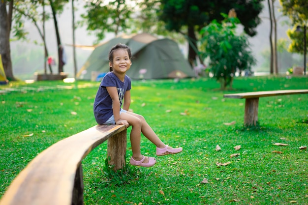 Petite fille assise sur un banc en allant camper