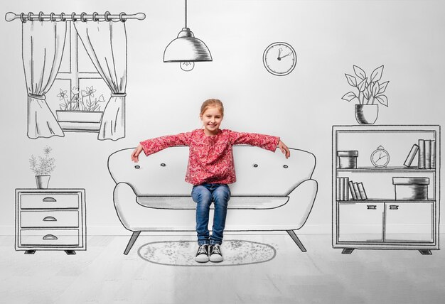 Petite fille assise sur un canapé à l'intérieur de la salle monochromatique