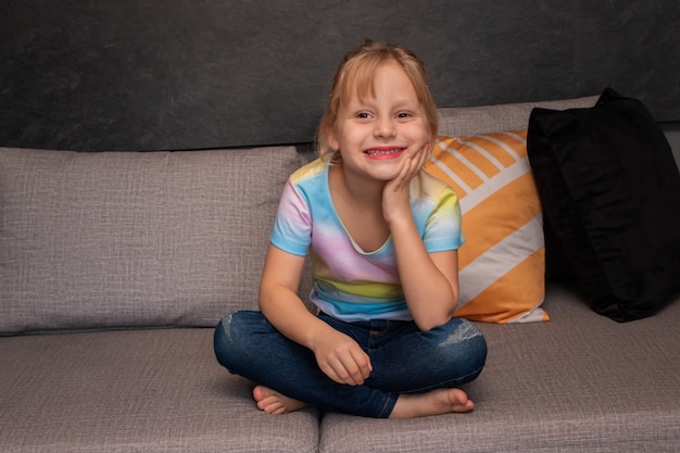 Petite fille assise sur le canapé