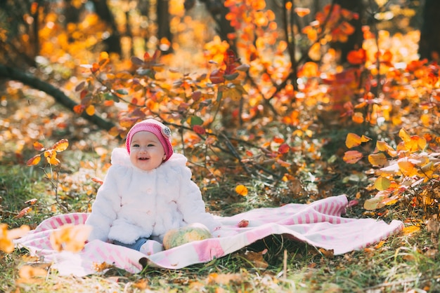 Petite fille assise sur une couverture dans la forêt d'automne