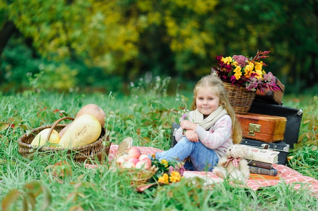 Petite fille assise sur une couverture sur l'herbe