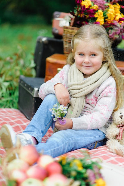 Petite fille assise sur une couverture sur l'herbe