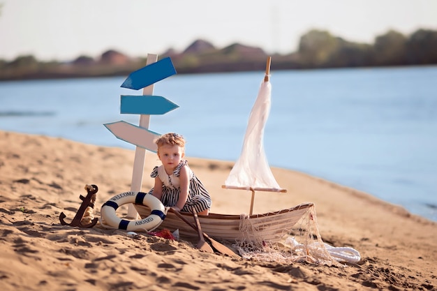 Petite fille assise dans un bateau sur une plage