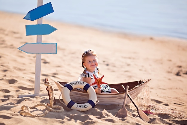 Petite fille assise dans un bateau sur une plage