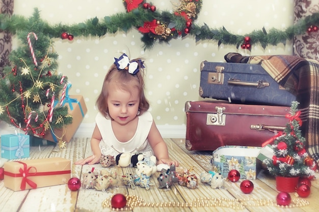 Petite fille assise devant un arbre de Noël et jouant avec des jouets