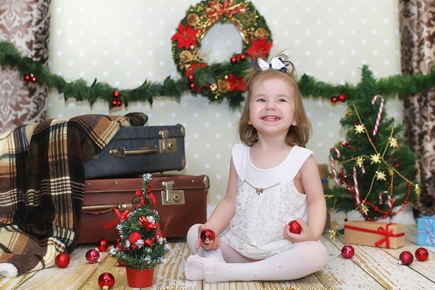 Petite fille assise devant un arbre de Noël