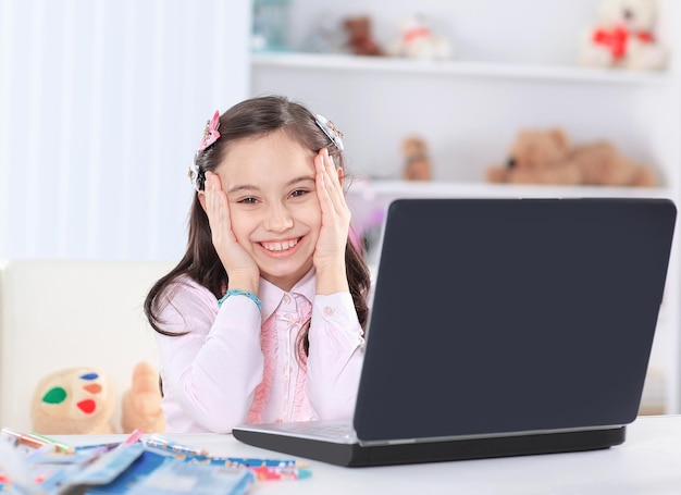 Petite fille assise devant un ordinateur portable ouvert dans sa chambre