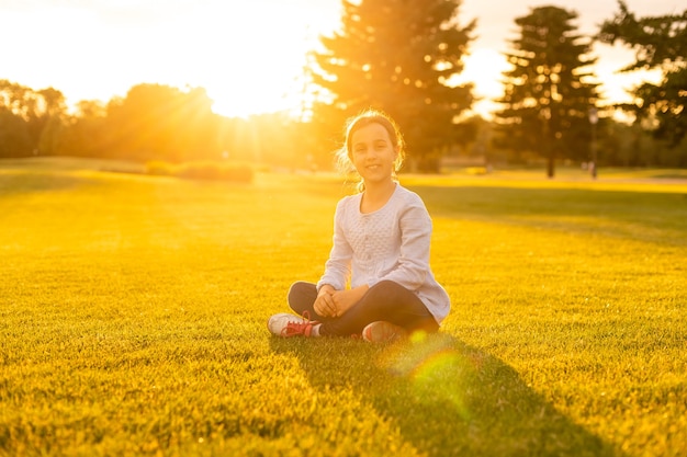 Petite fille assise sur l'herbe dans le parc.