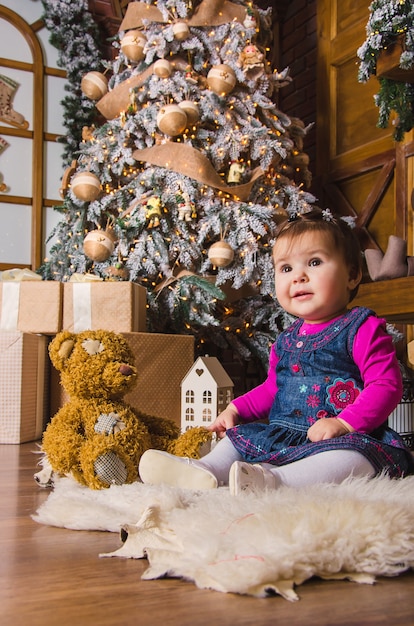 petite fille assise avec des jouets près de l'arbre de noël