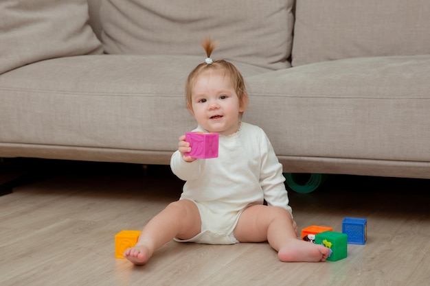 Petite fille assise à la maison sur le sol jouant des cubes développement de l'enfant