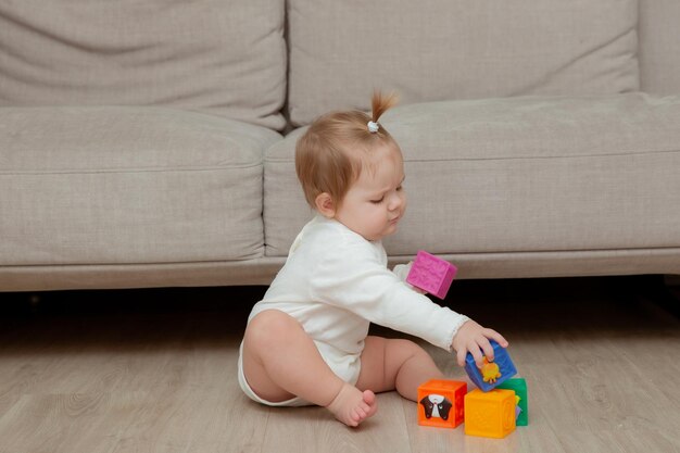 Petite fille assise à la maison sur le sol jouant des cubes développement de l'enfant