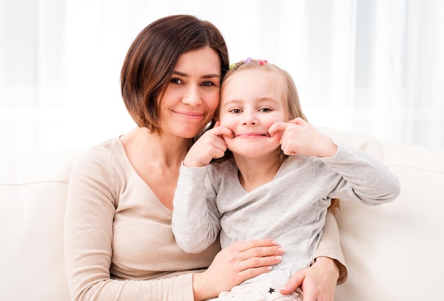 Petite fille assise avec maman et faisant des grimaces