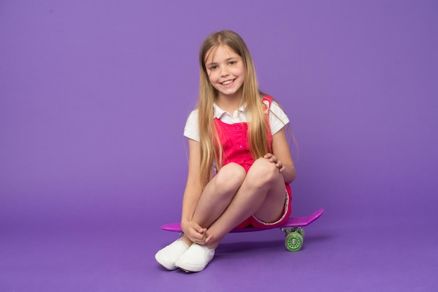 Petite fille assise sur une planche de penny Petite fille aime l'activité motrice Activité d'enfance Croisière d'aventure en aventure Penny board est le compagnon de voyage ultime