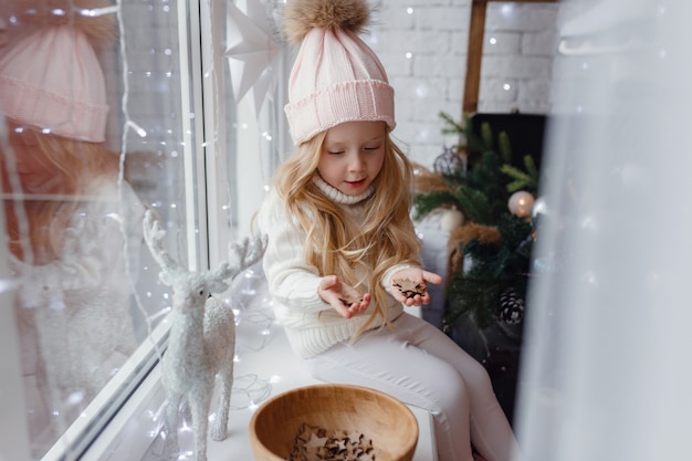 Petite fille assise sur un rebord de fenêtre le matin de Noël.