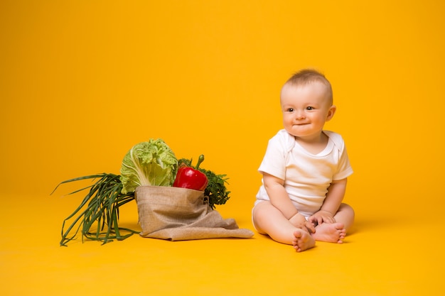 Petite fille assise avec sac de légumes jaune