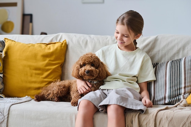 Petite fille assise avec son animal de compagnie à la maison