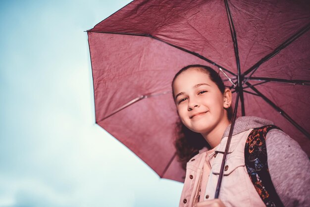 Petite fille attendant le bus le jour de la pluie