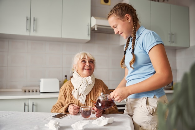 Petite-fille Attentionnée Offrant Du Thé à Sa Grand-mère