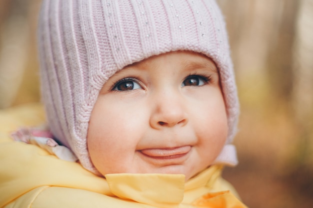 Une petite fille au chapeau chaud sur la tête sourit. enfance, santé, FIV, temps froid