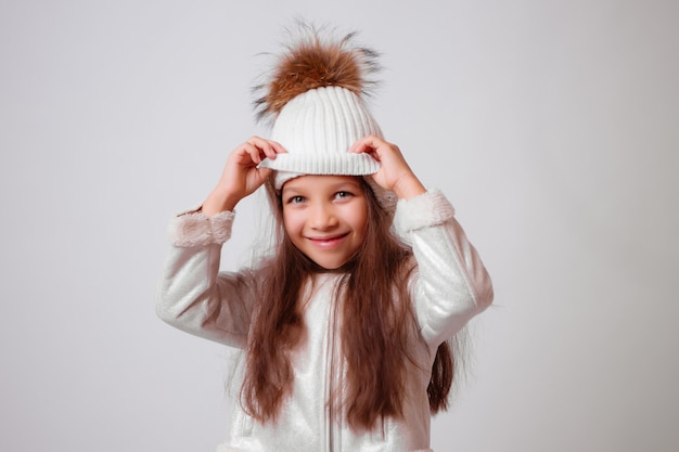 petite fille au chapeau d'hiver souriant sur blanc