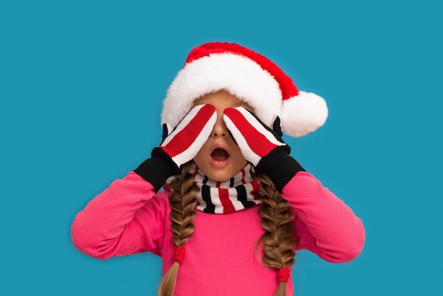 Photo la petite fille au chapeau de noël posa ses mains sur ses yeux.