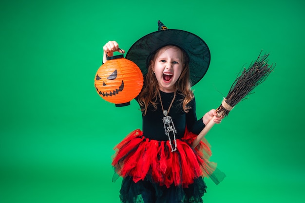 Petite fille au chapeau noir et costume de sorcière avec balai