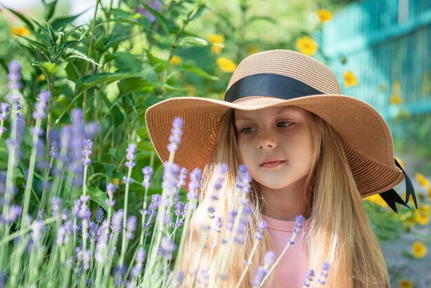 Petite fille au chapeau de paille entourée de fleurs de lavande