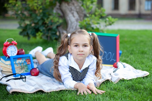 petite fille au déjeuner et apprend sur une pelouse dans le parc.