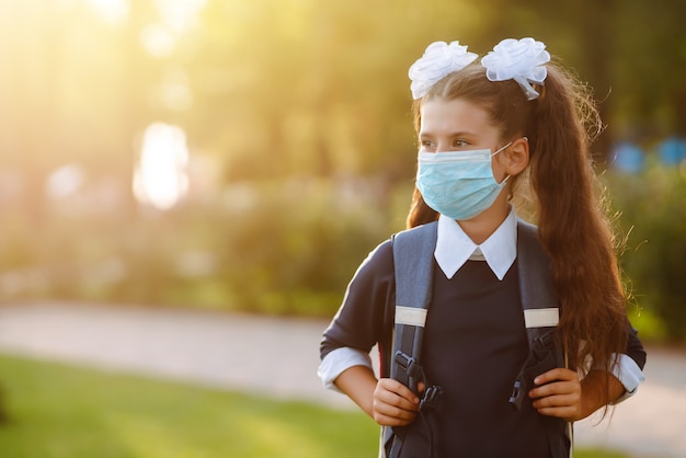 Petite fille au masque médical Retour à l'école. Écolière portant un masque médical.