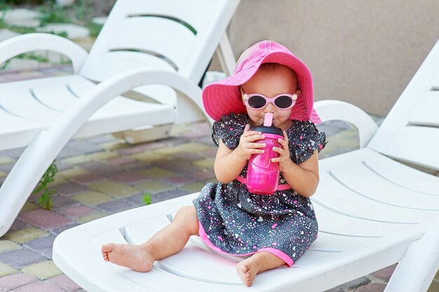 Petite fille en automne parc boit de la bouteille en plastique rose.