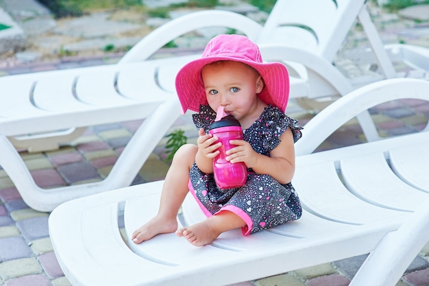 Petite fille en automne parc boit à partir d&#39;une bouteille en plastique rose