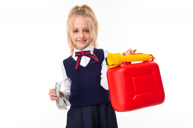 Une petite fille aux cheveux blonds farcis dans une queue de cheval, de grands yeux bleus et un joli visage détient de l'argent et une boîte de jouets.